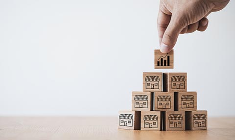 Hand building a tower of wooden houses with a growth chart